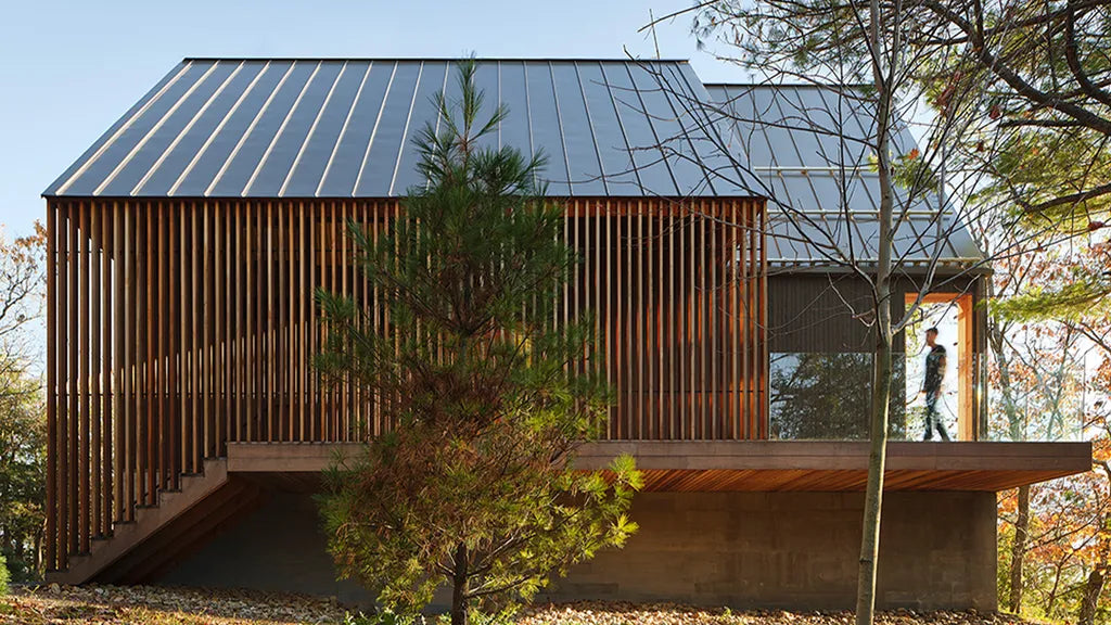 small modern cabin in mountain forest with photovoltaic array and large framed windows